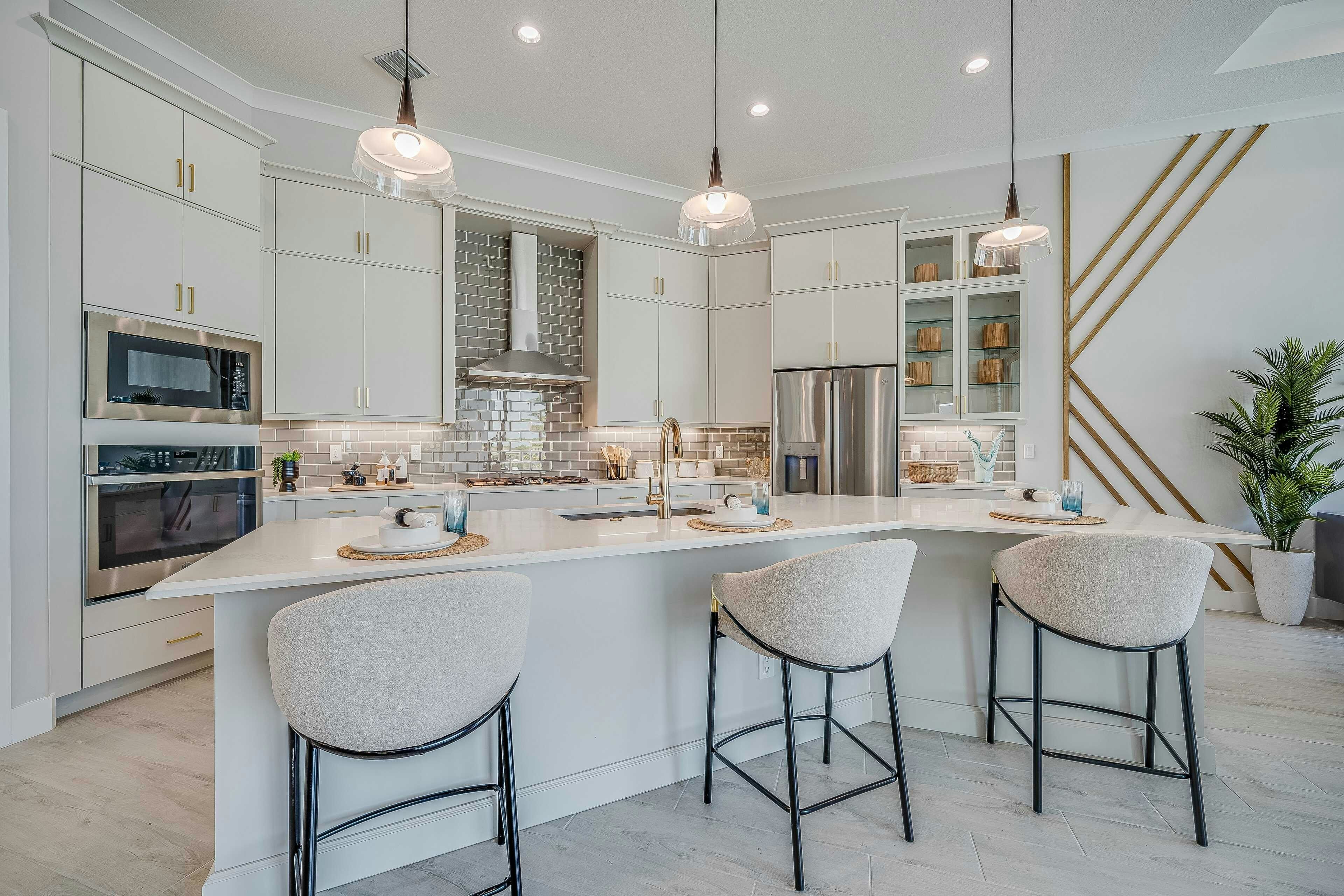 Island Kitchen with white cabinets, quarts and gold accents. grey tile backsplash