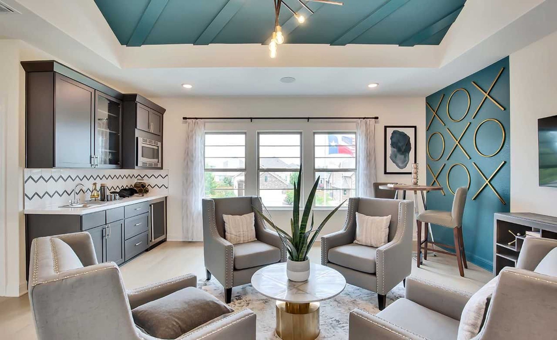 Luxurious living area with velvet chairs, marble-top table, and geometric accent wall in Oaks at San Gabriel, Texas.