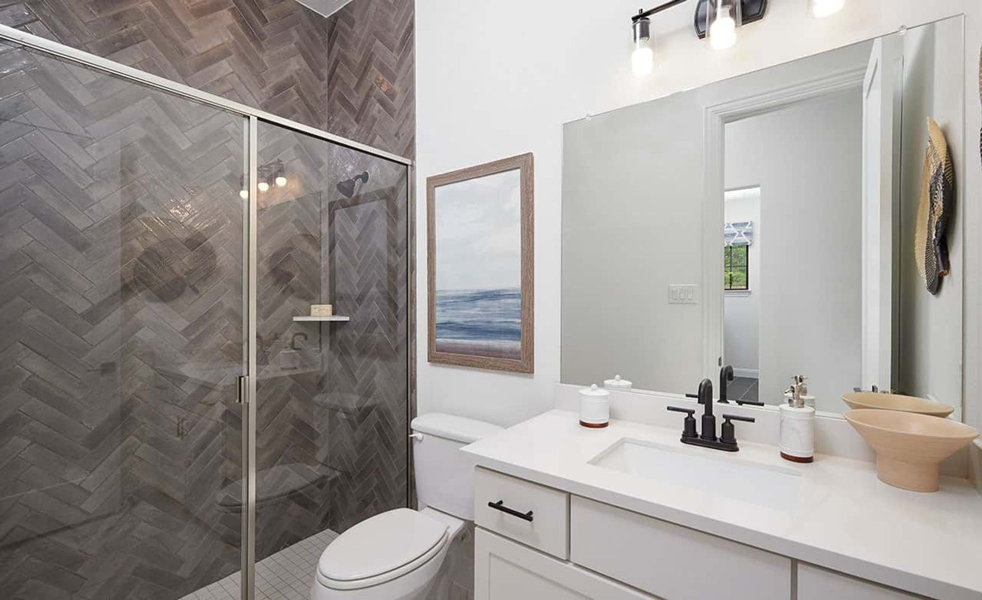 This Anthem bathroom showcases exquisite herringbone tile and sleek modern fixtures for sophisticated living.