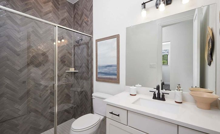 This Anthem bathroom showcases exquisite herringbone tile and sleek modern fixtures for sophisticated living.