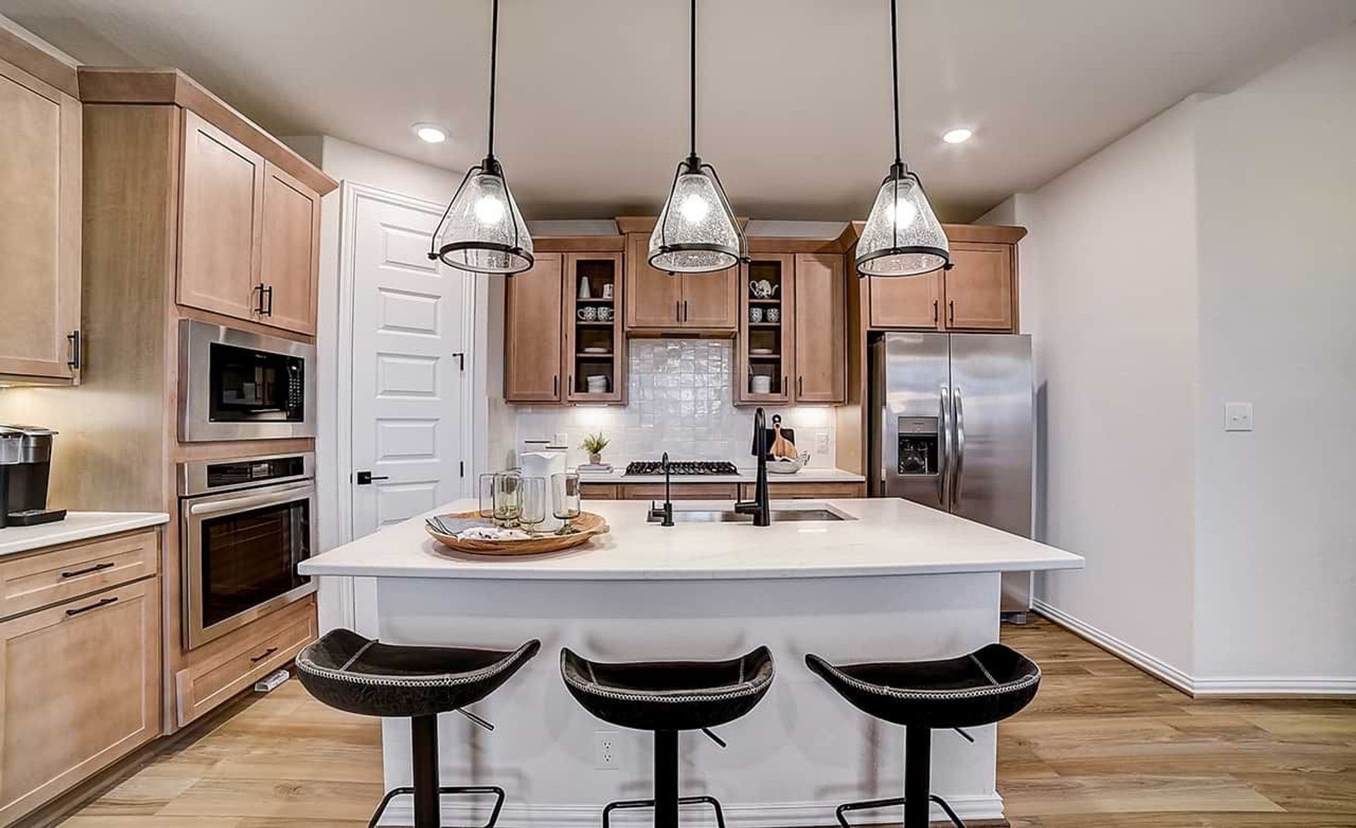 Dauer Ranch kitchen boasts elegant pendant lighting, sleek wood cabinetry, and a stylish island centerpiece.