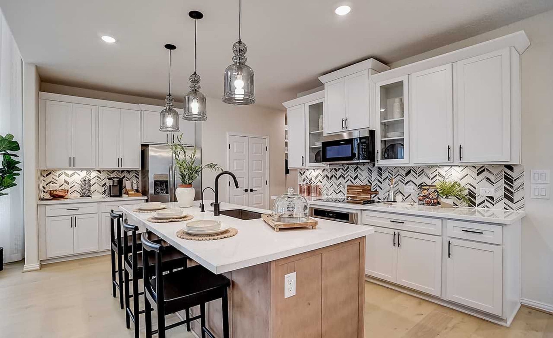 Elegant kitchen with herringbone backsplash, sleek cabinetry, and island in Casinas at Gruene.