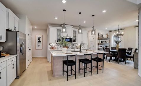 Elegant kitchen in Casinas at Gruene features high-end fixtures, large island, and herringbone backsplash.