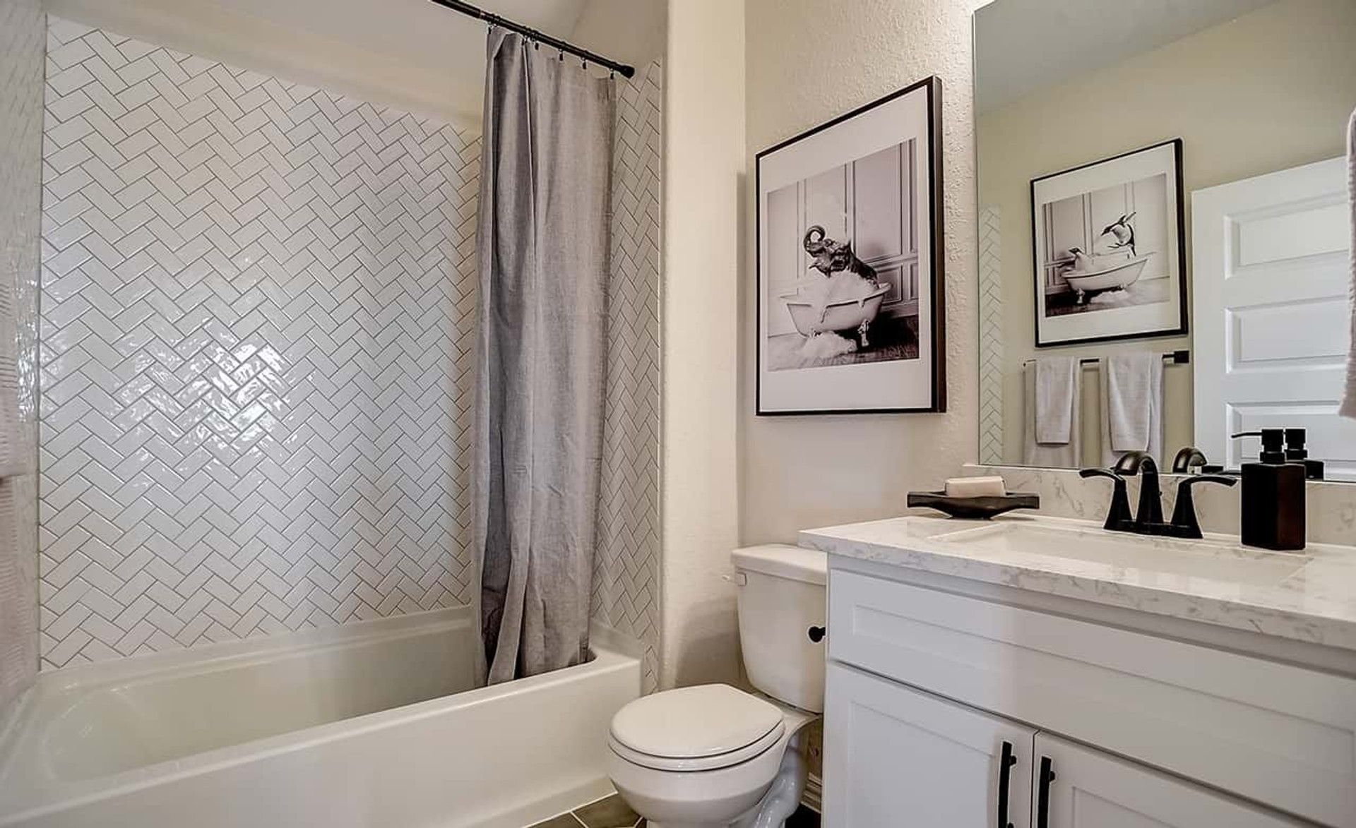 Elegant herringbone tile and sleek marble vanity define this Casinas at Gruene bathroom.