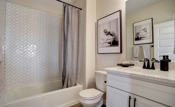Elegant herringbone tile and sleek marble vanity define this Casinas at Gruene bathroom.