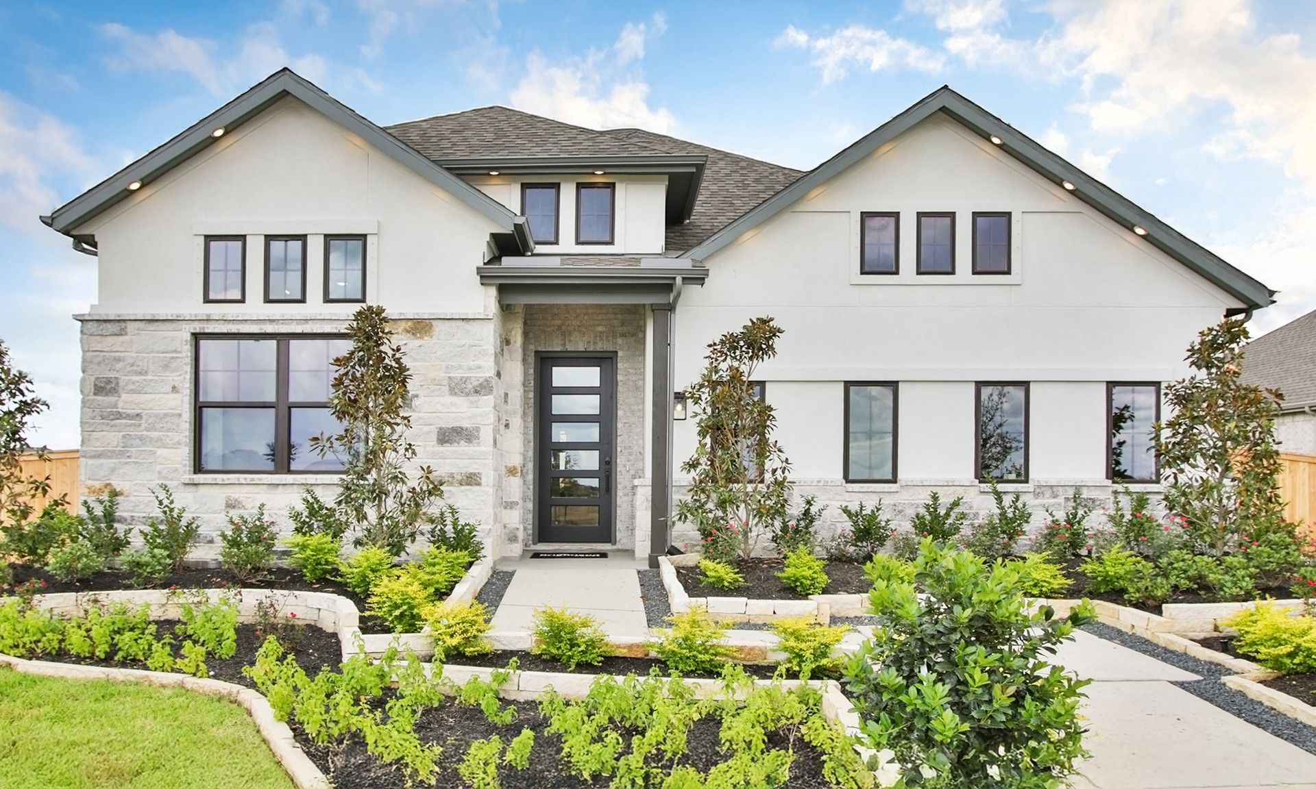 Elegant white facade with stone accents and pristine landscaping in Coastal Point community.
