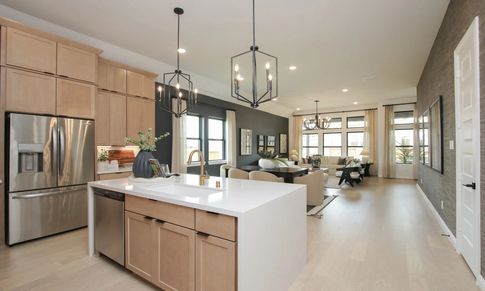 Elegant open-concept design with light wood floors and modern chandeliers in Coastal Point.