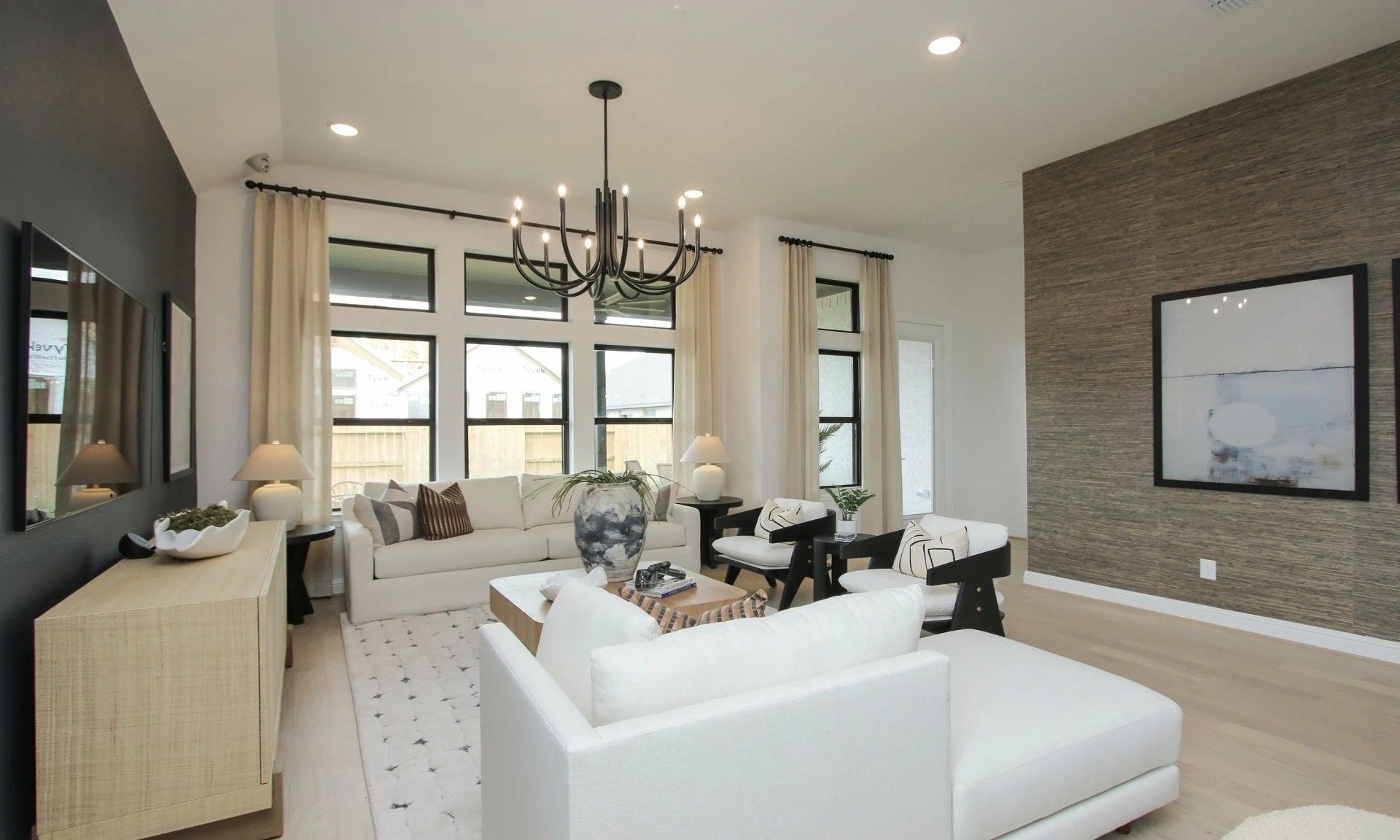 Discover elegance in Coastal Point's living room. Modern chandelier, textured accent wall elevate luxury design.