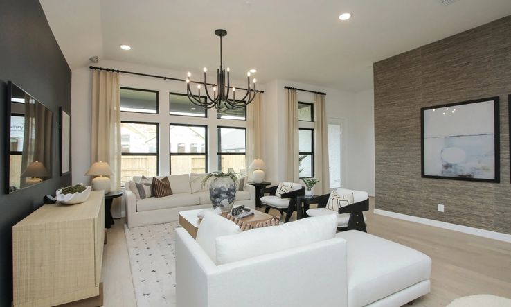 Discover elegance in Coastal Point's living room. Modern chandelier, textured accent wall elevate luxury design.