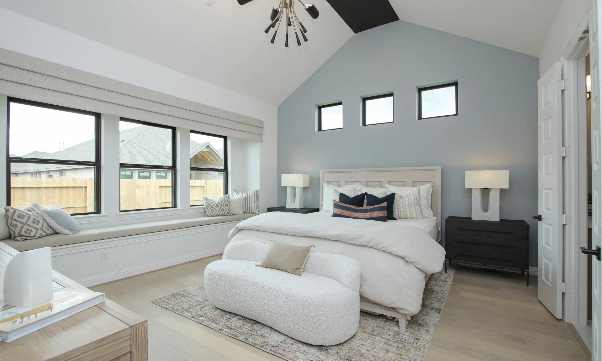 Vaulted ceiling, chic lighting, and expansive windows define this luxury Coastal Point bedroom. Exclusive living space.