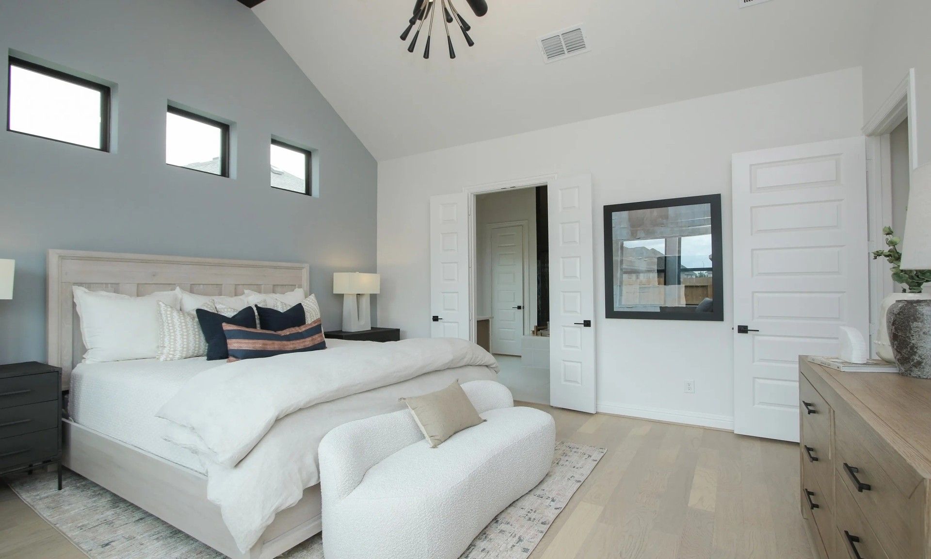 Elegant vaulted ceiling and modern lighting highlight the serene bedroom in Coastal Point, Texas.