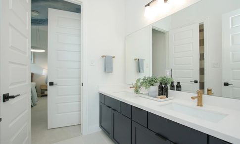 Elegant dual sinks paired with chic gold fixtures and spacious black cabinetry in Coastal Point.