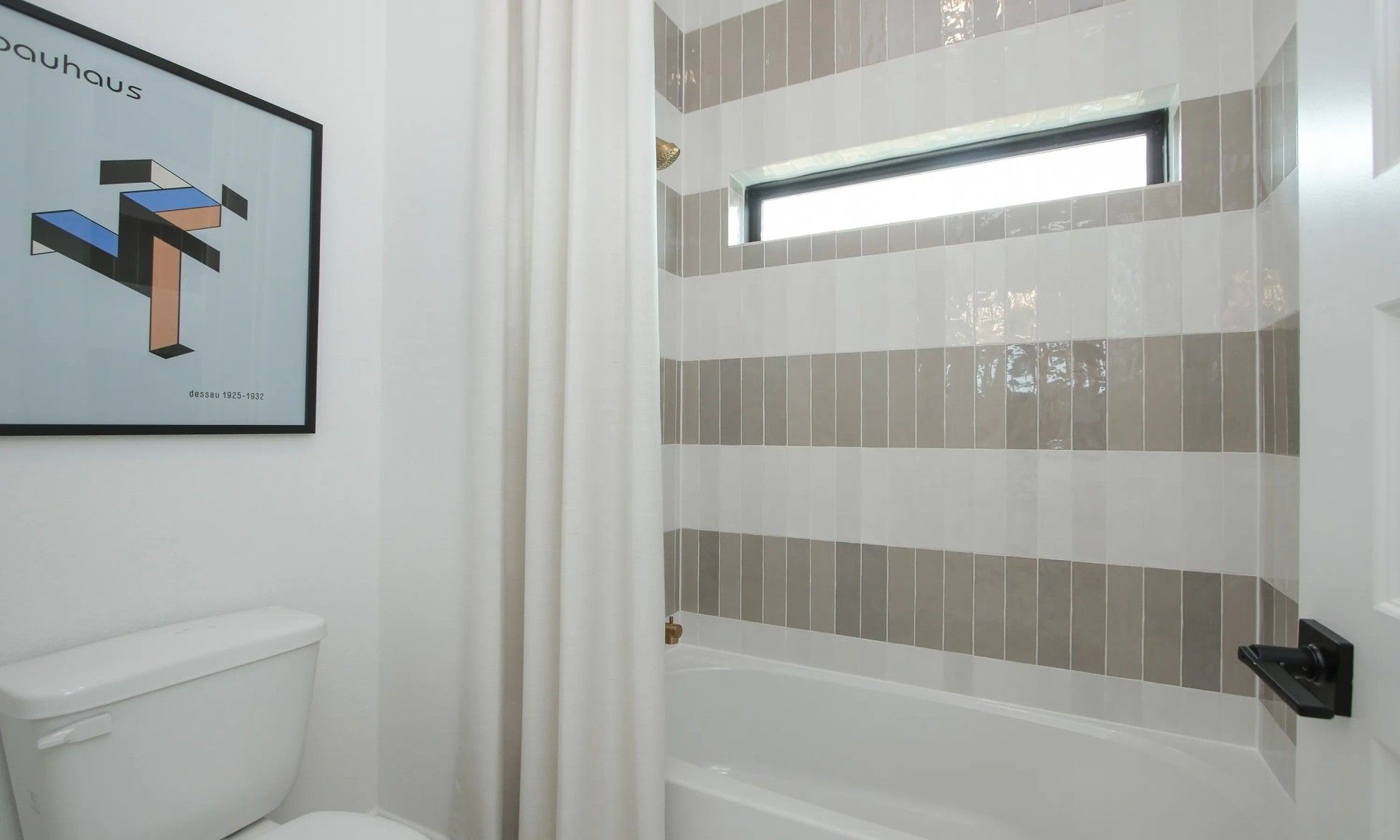 Elegant striped tiles and sleek fixtures enhance this Coastal Point bathroom's modern allure.