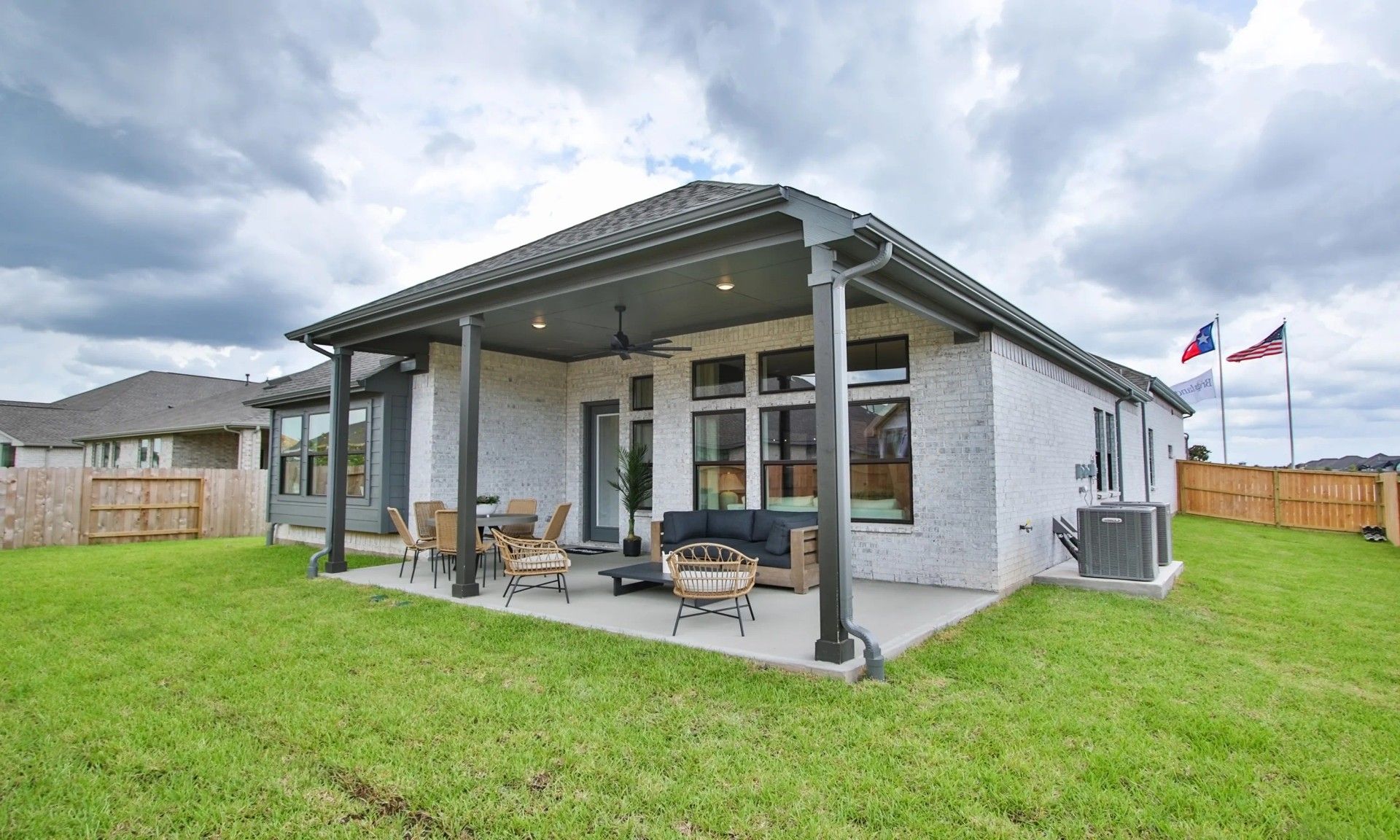 Spacious patio with ceiling fans and sleek brick exterior epitomizes luxury in Coastal Point, Texas.