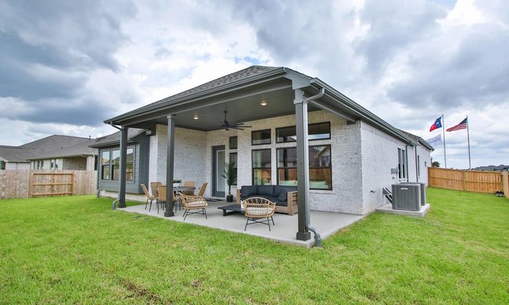 Spacious patio with ceiling fans and sleek brick exterior epitomizes luxury in Coastal Point, Texas.