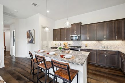 Experience luxury with granite countertops and elegant herringbone backsplash in Heritage Park's sophisticated kitchen.