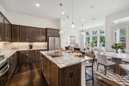 Granite countertops, dark wood cabinetry, and an open floor plan define this Heritage Park luxury kitchen.