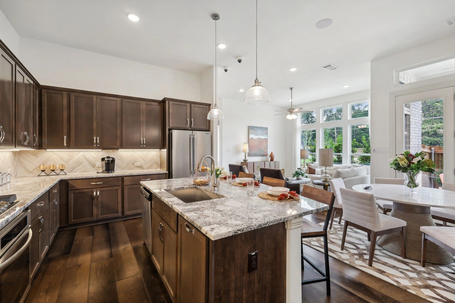 Granite countertops, dark wood cabinetry, and an open floor plan define this Heritage Park luxury kitchen.