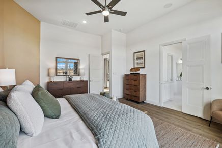 Luxurious Solterra bedroom with sleek wood flooring, elegant neutral palette, and stylish ceiling fan.