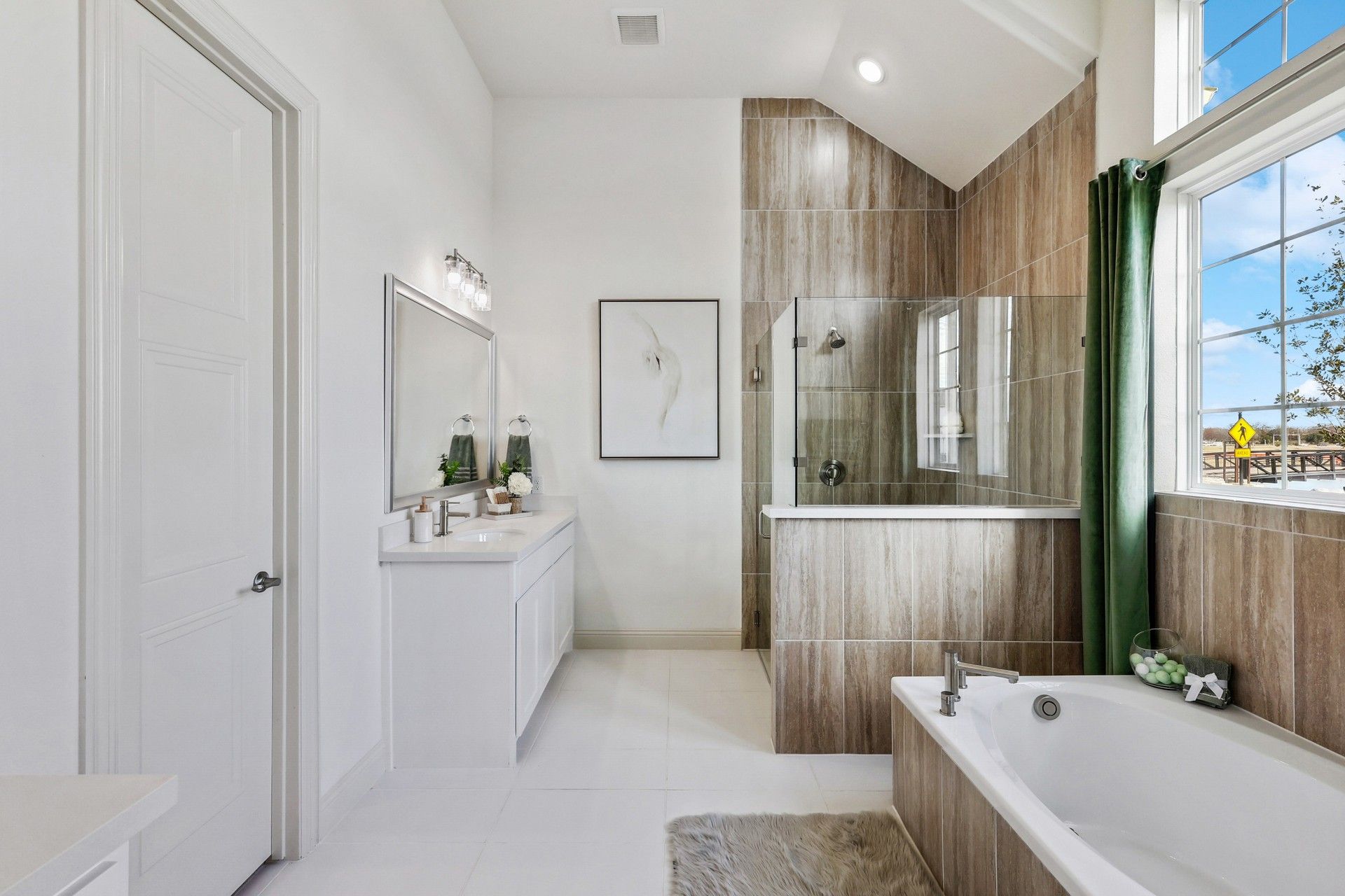 Experience luxury with a glass shower, chic tub, and expansive mirror in Solterra, Texas. Tailored for elegance.