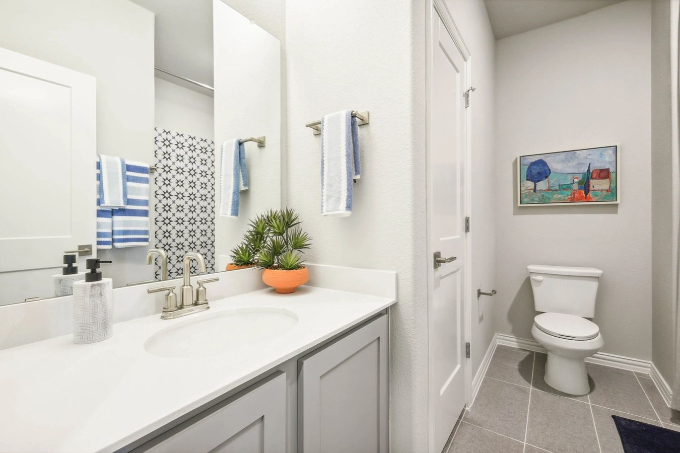 Luxurious white vanity and stylish tiles highlight this Pebblebrook community bathroom.