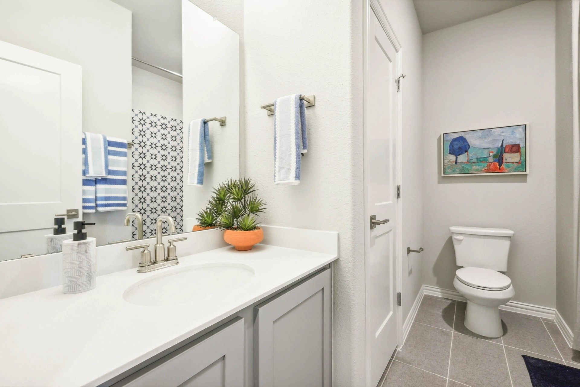 Luxurious white vanity and stylish tiles highlight this Pebblebrook community bathroom.
