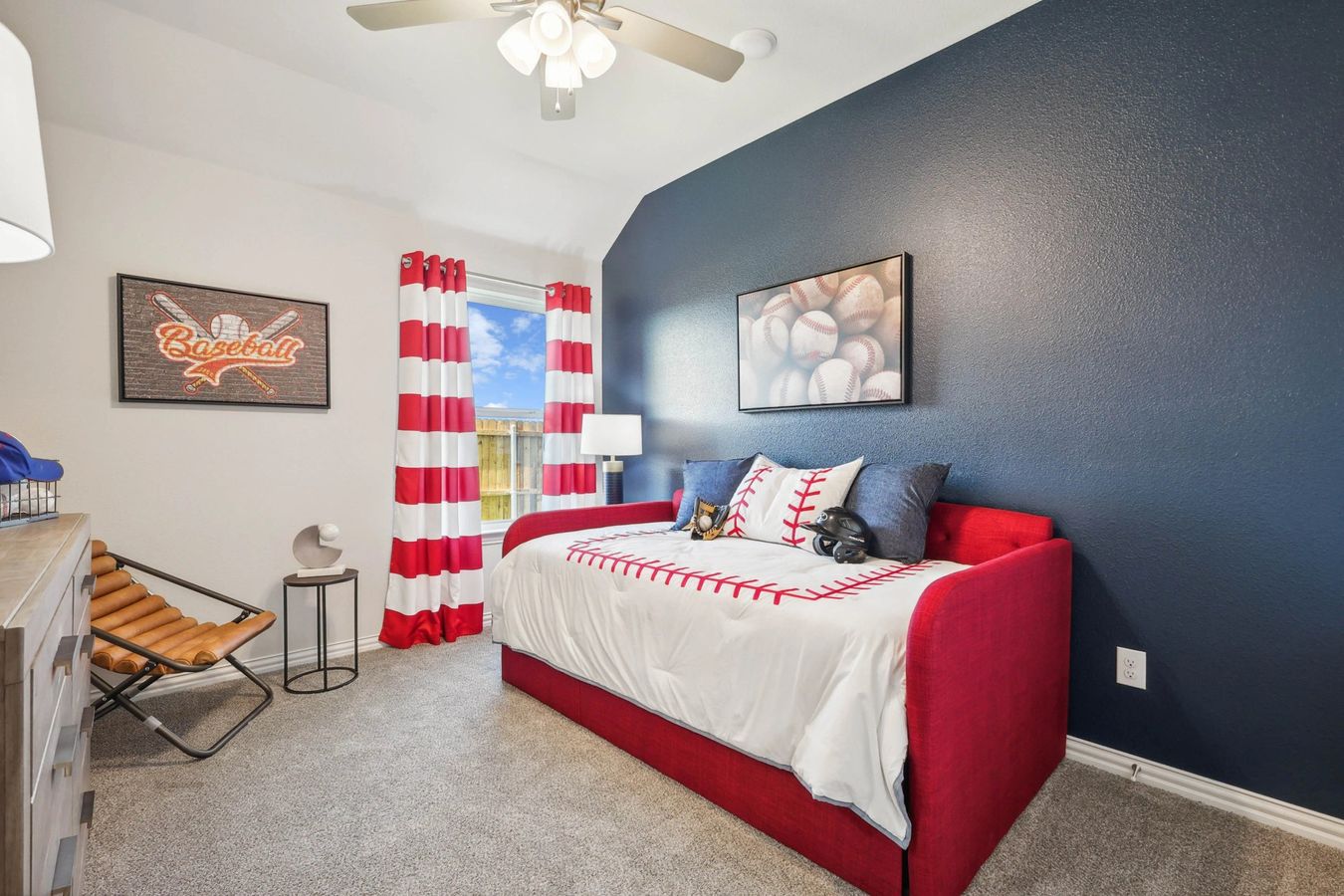 Luxurious Pebblebrook bedroom with bold navy accent wall, tailored red daybed, and sporty decor.
