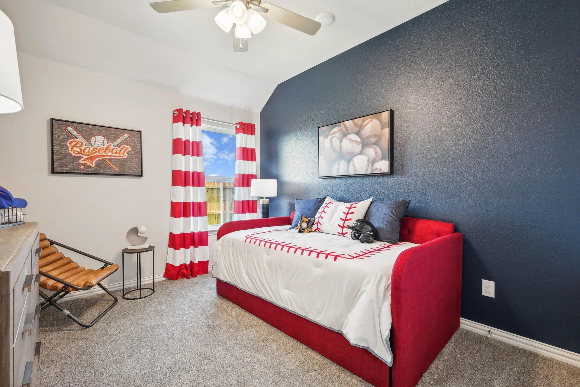 Luxurious Pebblebrook bedroom with bold navy accent wall, tailored red daybed, and sporty decor.