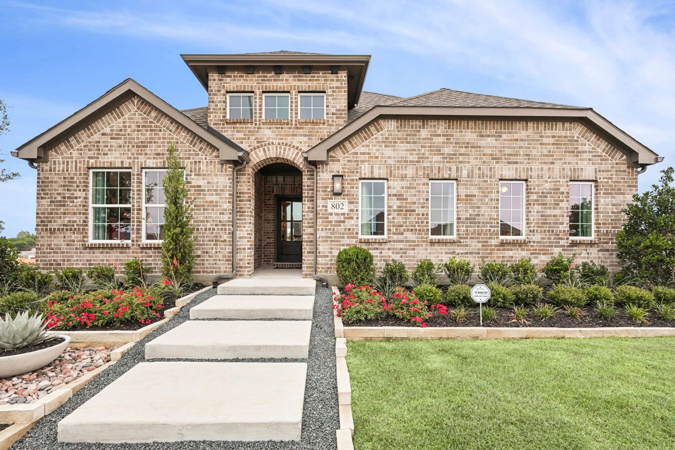 Stunning brick facade with elegant arched entryway and lush gardens at Simpson Crossing.