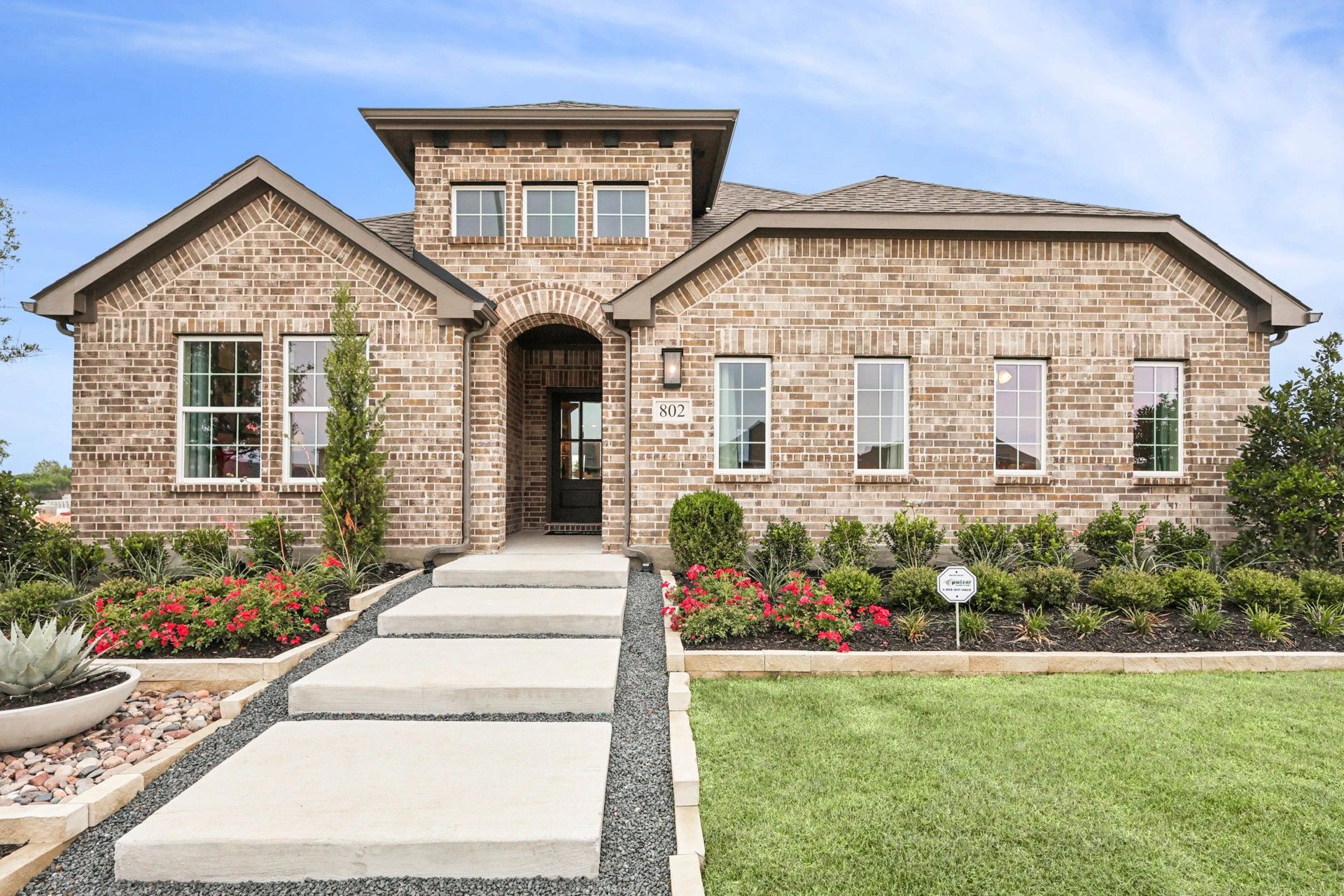 Stunning brick facade with elegant arched entryway and lush gardens at Simpson Crossing.