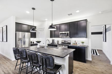 This Simpson Crossing kitchen features sleek dark cabinetry and a refined stone island, blending elegance with functionality.