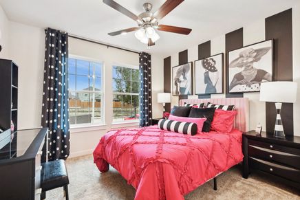 Simpson Crossing's bedroom features chic pink bedding, striped wall art, and elegant polka dot accents.