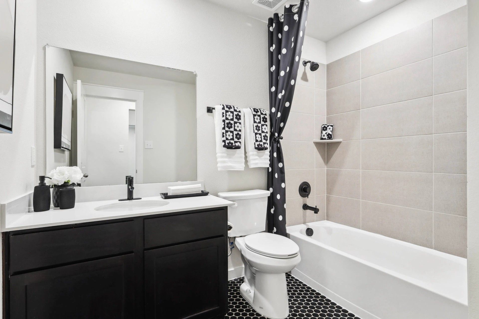 Experience timeless elegance with sleek black vanity and hex tile flooring in Simpson Crossing's luxurious bathroom.