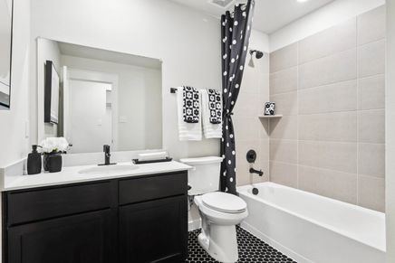 Experience timeless elegance with sleek black vanity and hex tile flooring in Simpson Crossing's luxurious bathroom.