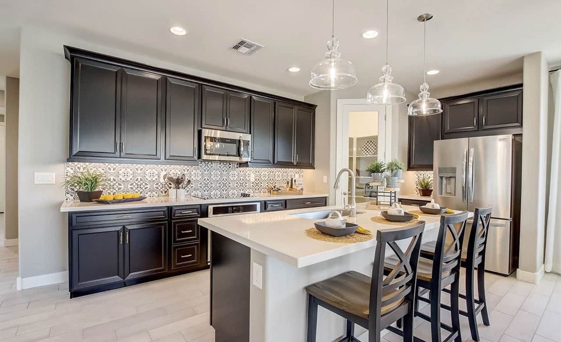 Elegant black cabinetry and intricate backsplash define this Castillo kitchen in Anderson Parc, Arizona.