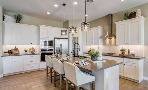 Elegant white cabinetry, sleek island, and refined lighting in a luxurious Hacienda community kitchen.