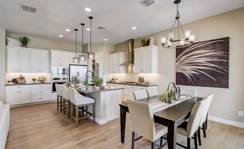 Exquisite kitchen boasts sleek white cabinets, chic pendant lighting, and refined wood flooring in Hacienda.
