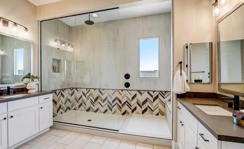 Experience opulence with chevron-tiled shower and sleek double vanity in Canyon Views' luxurious Hacienda home.