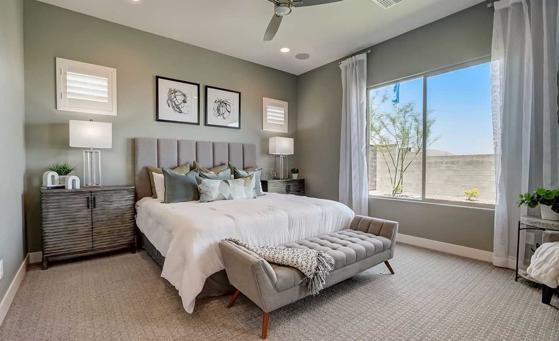 Sophisticated bedroom features plush fabrics, elegant tufted bench, and expansive window in Canyon Views.