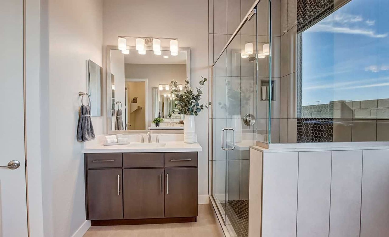 Luxurious glass shower and sleek wood vanity elevate this Mirada Crossing bathroom.