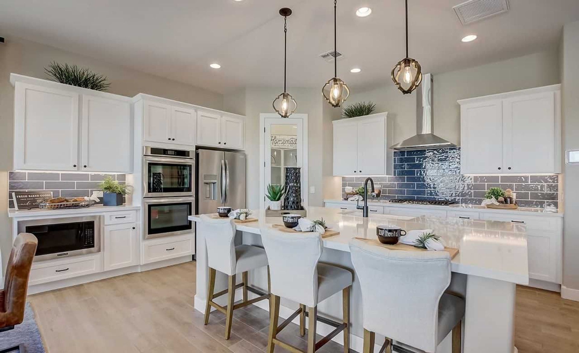Luxurious Mirada Crossing kitchen featuring sleek white cabinetry and a striking blue tile backsplash.