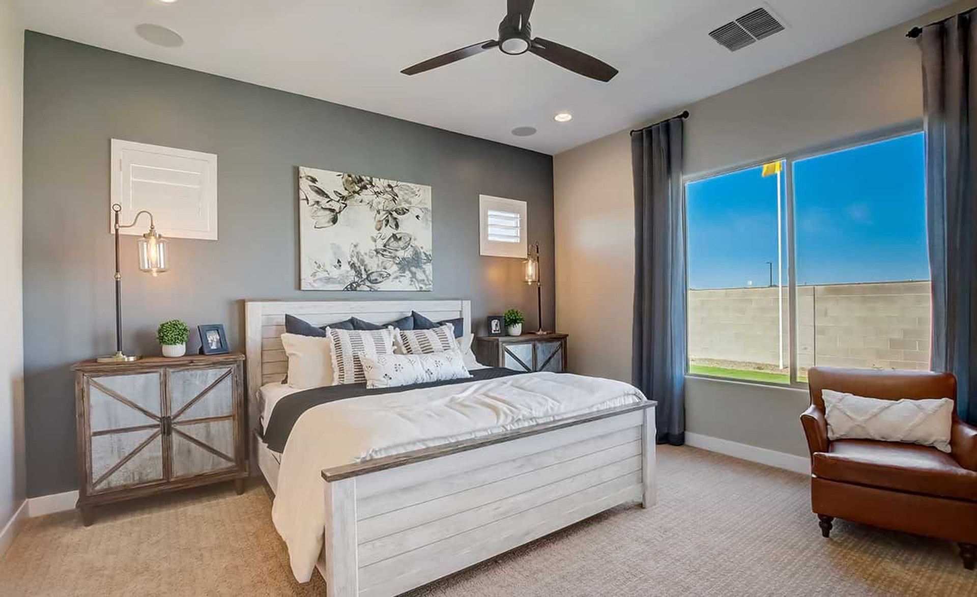Discover refined comfort in Mirada Crossing's bedroom with sleek gray walls, chic lighting, and timeless wooden furniture.