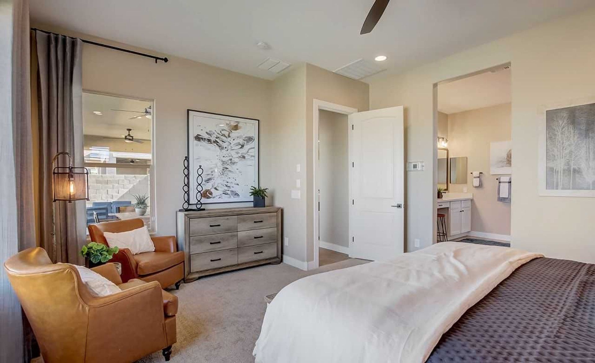 Sophisticated bedroom with leather seating and en-suite bath in Mirada Crossing, offering modern luxury and comfort.