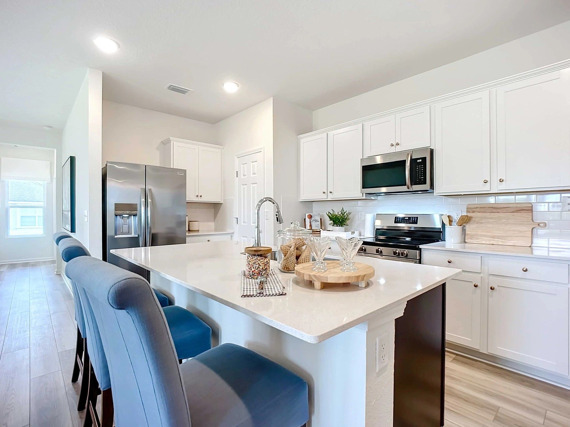 Luxurious kitchen in Panther Creek boasts sleek white cabinetry, marble island, and premium stainless appliances.