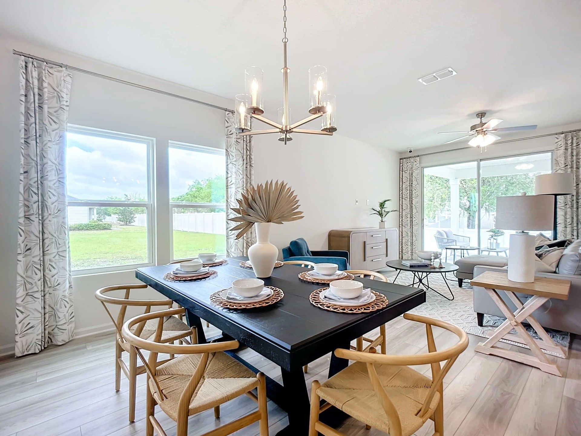 Luxurious dining space features a chic chandelier and expansive windows in Panther Creek.