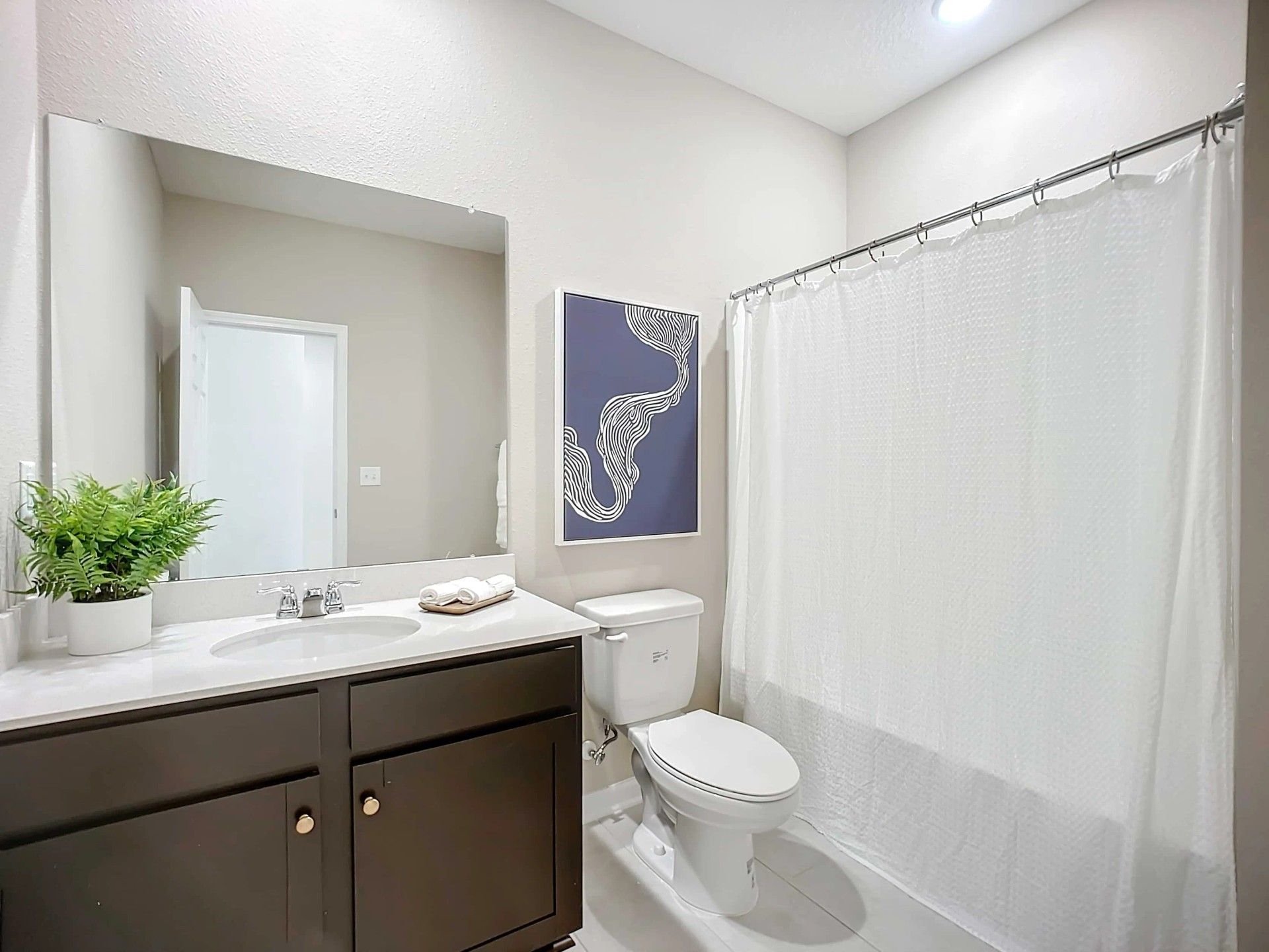 Sophisticated bathroom features sleek dark cabinetry and elegant white accents in Panther Creek.