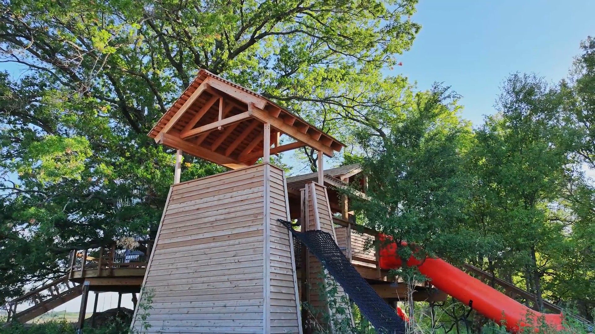 Exceptional wooden treehouse with a vibrant slide offers unparalleled charm amid the trees of Solterra, Texas.