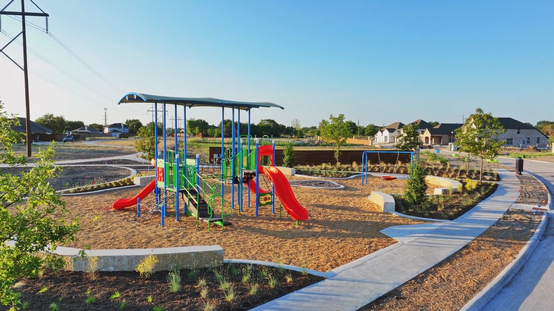 Explore Solterra's exquisite playground featuring vibrant, modern equipment and beautiful curved pathways amid lush landscaping.