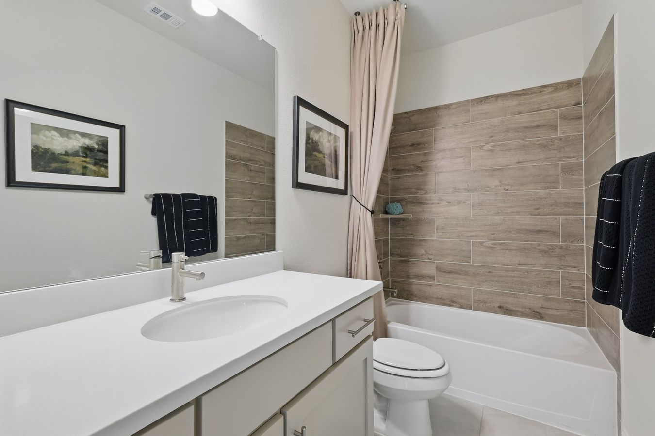 Step into sophistication with sleek wood-patterned tiles and a pristine vanity in Kelly Ranch.