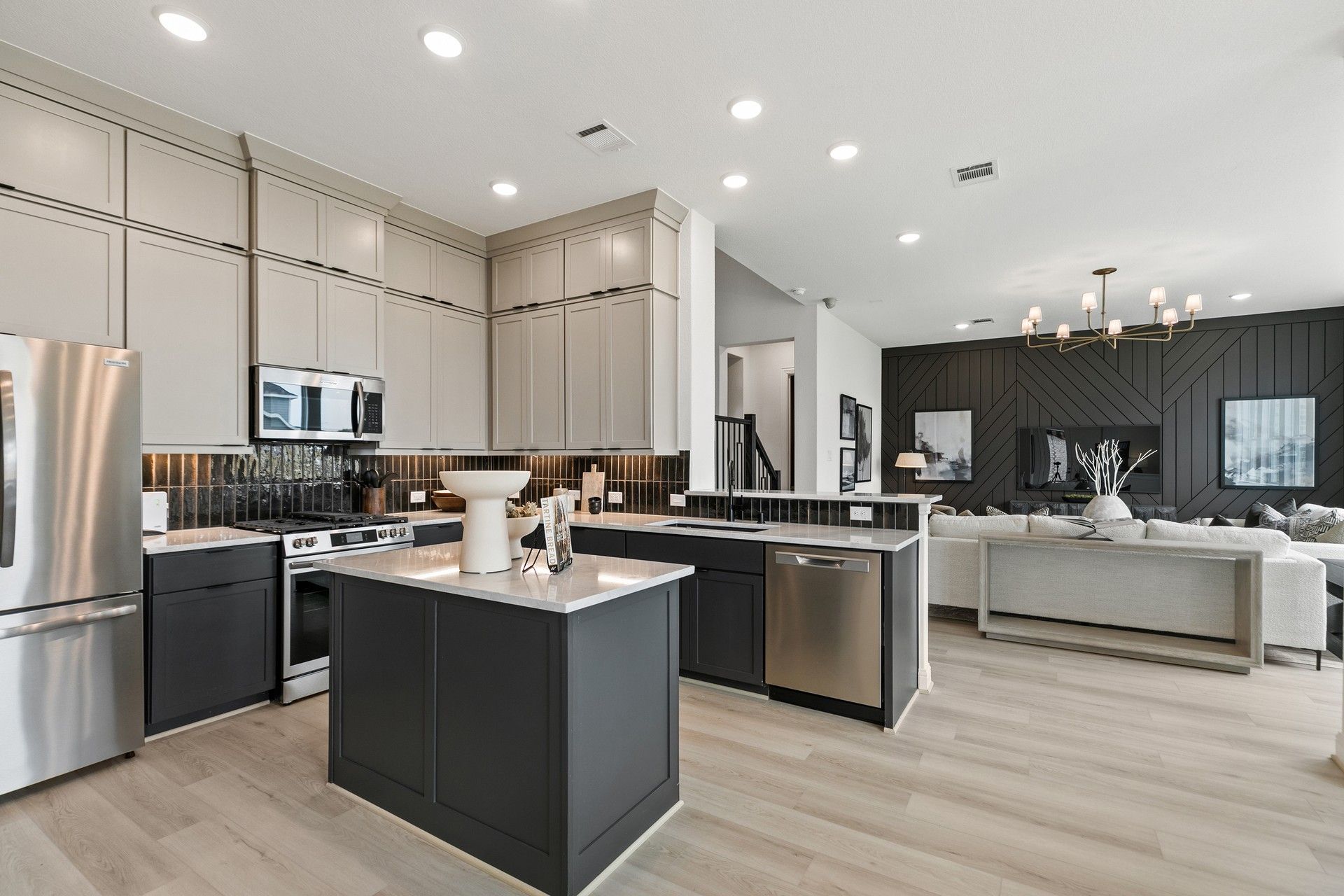 Elegant modern kitchen with premium finishes, island, and wood accent wall in Park at Eldridge, Texas.